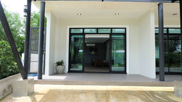 A modern building entrance with glass doors, a concrete platform, and a potted plant. - Rublom & Chomview Huahin Pranburi (Pranburi)