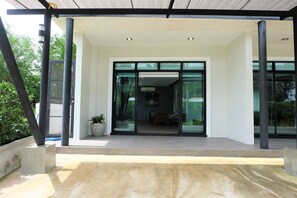 Una entrada de edificio moderna con puertas de vidrio, una plataforma de hormigón y una planta en maceta.