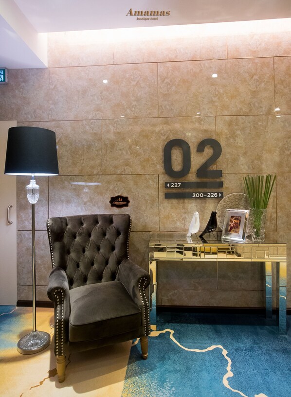 A lobby with a tufted armchair, a reception desk, and a floor lamp.