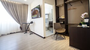 Une chambre d’hôtel moderne dotée d’une grande fenêtre, d’un fauteuil, d’un bureau et d’un téléviseur.