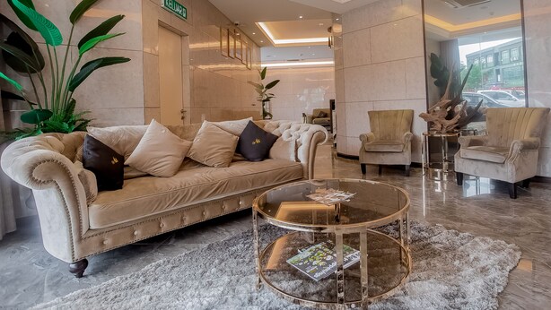 Un hall d’hôtel avec un canapé beige moelleux, une table basse en verre et un grand miroir qui reflète la pièce.