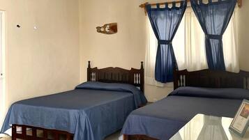 A room with two wooden beds, a ceiling fan, an air conditioning unit, and a glass table.
