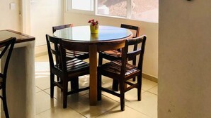 A dining area with a round table and chairs, a window with a view of the beach, and a surfboard decoration on the wall. - Bungalows Las Hamacas (San Patricio Melaque)