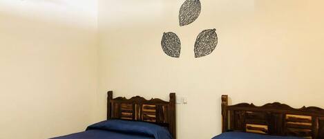 Una habitación con dos camas individuales, un ventilador de techo y una decoración en la pared.