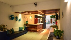 A reception area with a wooden reception desk, a seating area with cushions, and a wall-mounted clock. - Bungalows Las Hamacas (San Patricio Melaque)
