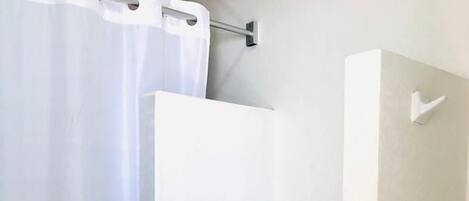 Un baño con inodoro, cortina de ducha y dispensador de jabón.