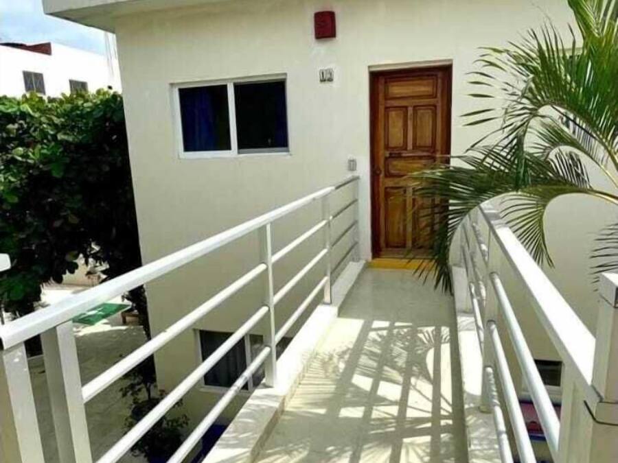 A white building with a wooden door, a small window, and a metal railing.