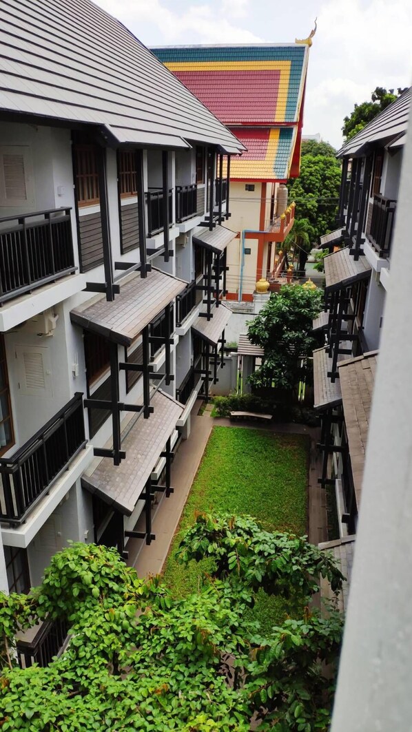 Un patio con varios edificios, cada uno con balcones y un jardín central.