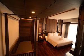 Ein Hotelzimmer mit Holzboden, einem großen Bett mit weißen Leinentüchern, einem Nachttisch mit Lampe und einem Fenster mit Vorhängen.