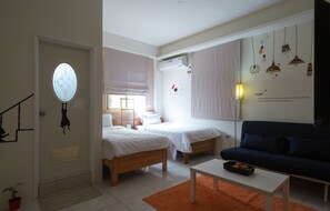 A modern bedroom with two beds, a sofa, a small table, and a wall with light fixtures.