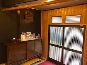 A reception area with a wooden counter, a small table, and a wall-mounted display. - Sakura (Manazuru)