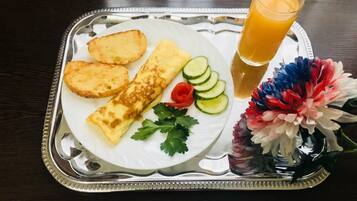 A tray with an omelette, cucumber slices, and a glass of orange juice.