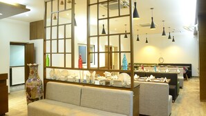 Un hall de hotel con zona de estar, un jarrón decorativo e iluminación colgante.