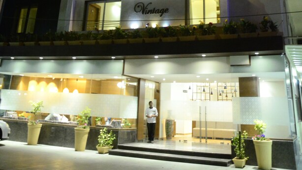Un hotel de varios pisos con balcones iluminados y una recepción decorada con plantas.