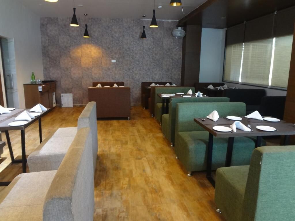 Un restaurante con cabinas y mesas, suelo de madera e iluminación colgante.