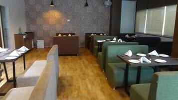 Un restaurante con cabinas y mesas, suelo de madera e iluminación colgante.