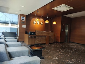 A hotel lobby with a reception desk, seating area, and a view of the outside.