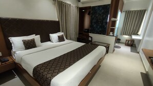 Habitación de hotel con una cama grande, un escritorio, una silla, una mesita y un espejo.