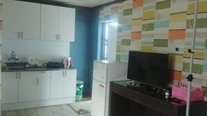 Una cocina con armarios blancos, una estufa y un televisor sobre un soporte de madera.