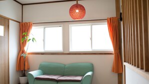 Una habitación con un sofá color turquesa, una planta en maceta y una ventana con cortinas.