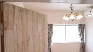 Una habitación con un ventanal grande, un armario de madera y una araña.
