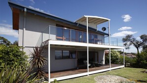 A modern two-story house with a balcony, large windows, and a deck area. - Ocean Pearl - Bunga St 61 (BERMAGUI)