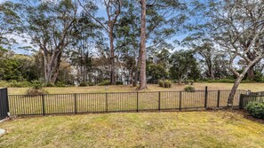A fenced yard with trees and grass.