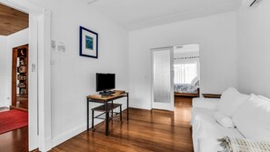 A modern living room with a white sofa, a wooden coffee table, and a television on a stand.