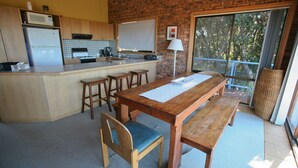 Eine Küche mit einem Holztisch, Bänken, einem Kühlschrank und einer Mikrowelle.