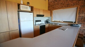 Eine kleine Küche mit Kühlschrank, Herd, Mikrowelle und Spüle.
