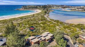 Une propriété située sur la côte, avec une enseigne indiquant « South Coast Accommodation », entourée de verdure et donnant sur une plage.