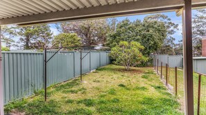 A backyard with a fenced area, a clothesline, and a small tree. - Mumbulla House - Mumbulla St 22a (BERMAGUI)