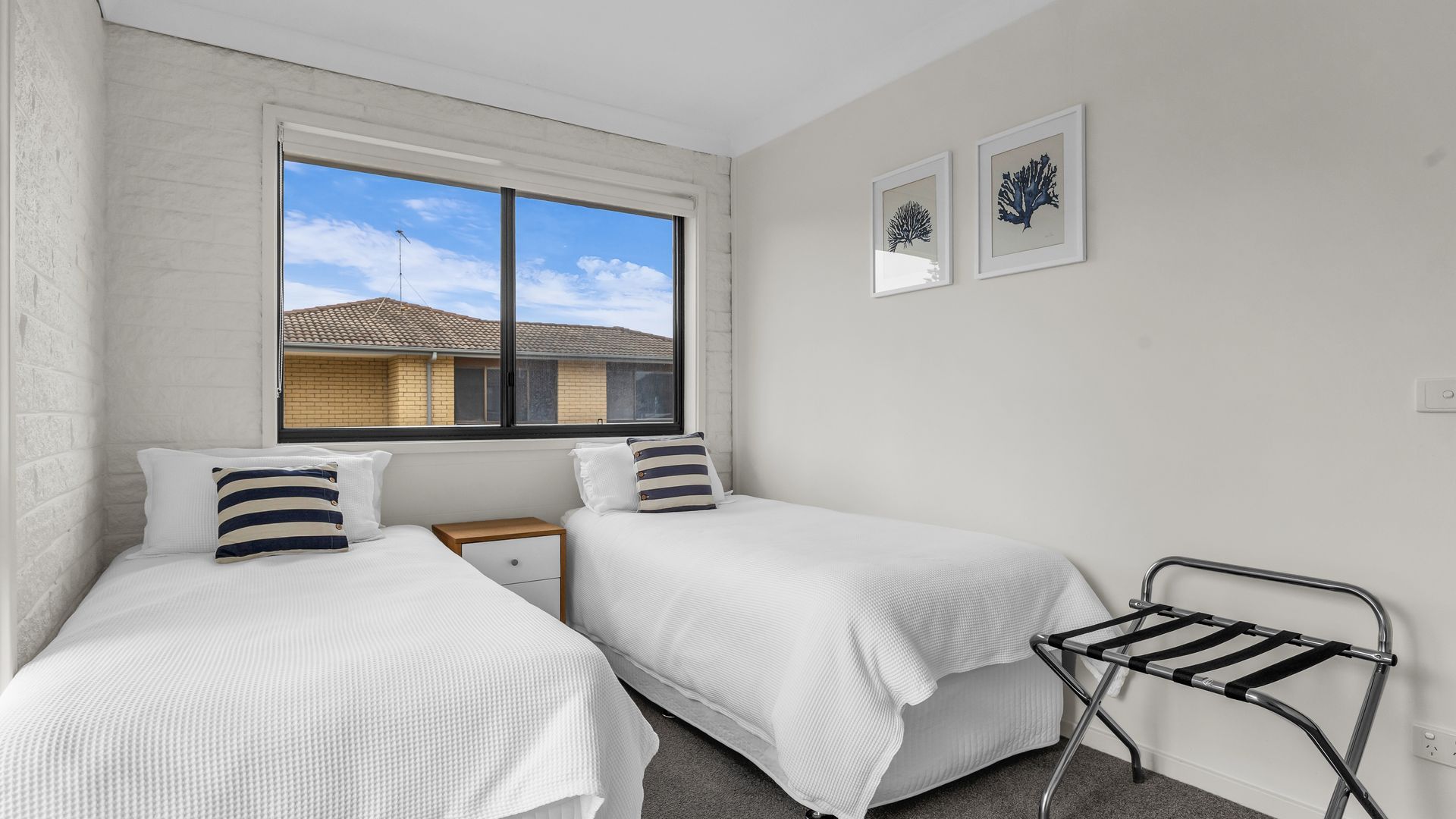 A bedroom with two beds, a window, and a drying rack.