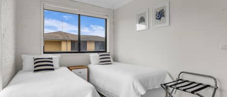 A bedroom with two beds, a window, and a drying rack.