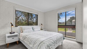 Une chambre à coucher avec un grand lit, deux tables de chevet et une fenêtre donnant sur l’extérieur.
