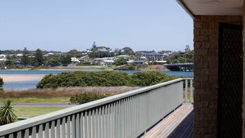 A balcony with a view of a beach, a bridge, and residential buildings.