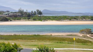 Un paysage côtier avec une plage, des maisons et une vue dégagée sur l’océan.