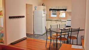 Une cuisine compacte équipée d’un réfrigérateur, d’une cuisinière et d’une table à manger avec des chaises.