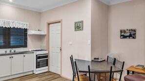 Una cucina compatta con piano cottura a gas, forno e mobili bianchi.