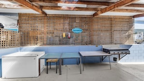 Un'area cucina all'aperto con una panca blu, un tavolo e un barbecue.