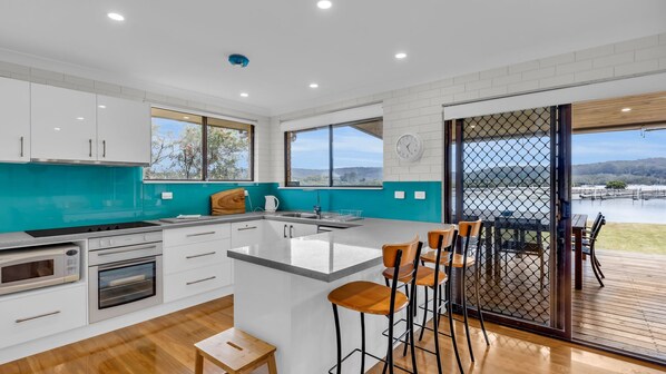 A modern kitchen with white cabinets, a teal backsplash, and a large island with bar stools.