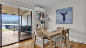 A dining area with a table and chairs, a bookshelf, and a framed picture of a whale's tail on the wall.