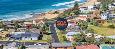 A coastal residential area with houses, a road, and a sign for South Coast Accommodation.