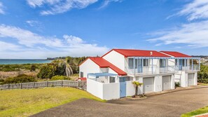 A coastal house with a red roof, a balcony, and a view of the sea.