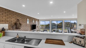 A modern kitchen with a brick wall, large windows, and a view of the outdoors.