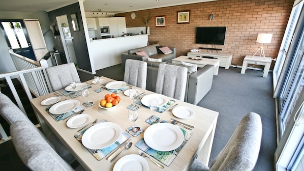 A modern kitchen with white cabinets, a microwave, and a TV mounted on a brick wall.
