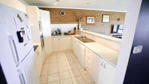 A compact kitchen with white cabinets, a tiled floor, a brick accent wall, and a sink.