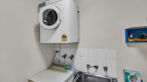 Un área de lavandería con lavadora, pileta e calentador de agua.