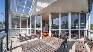 Un bâtiment moderne doté de grandes fenêtres en verre et d’un patio aménagé avec du mobilier en bois.