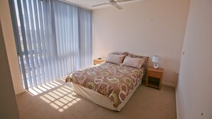 Ein Schlafzimmer mit einem Bett, einem Nachttisch, einer Lampe und einem Deckenventilator.
